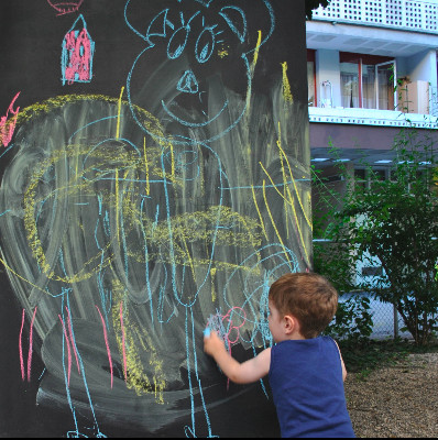 enfant dessinant sur un tableau noir